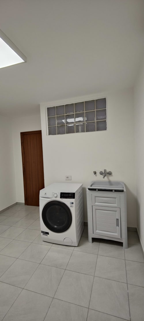 Moderna lavanderia con lavatrice e asciugatrice bianche in appartamento