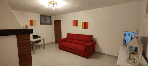 Divano rosso in ampio soggiorno con TV, scrivania e comfort moderni all'appartamento Villa Italia