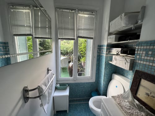 Salle de bain à Maison 1850 Paris Porte Montmartre avec carrelage turquoise, toilettes et portes donnant sur le jardin