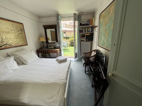 Chambre lumineuse à Maison 1850 Paris avec lit queen-size, vue sur jardin par portes vitrées, bureau, bibliothèques et accès à la terrasse