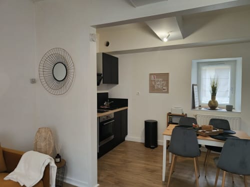 Cuisine et salle à manger modernes à Dinan avec meubles noirs, table en bois et vue sur la ville