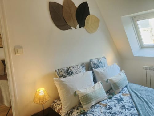 Chambre douillette à La Conciergerie de Nathalie à Dinan avec décor mural en feuilles et literie à motifs