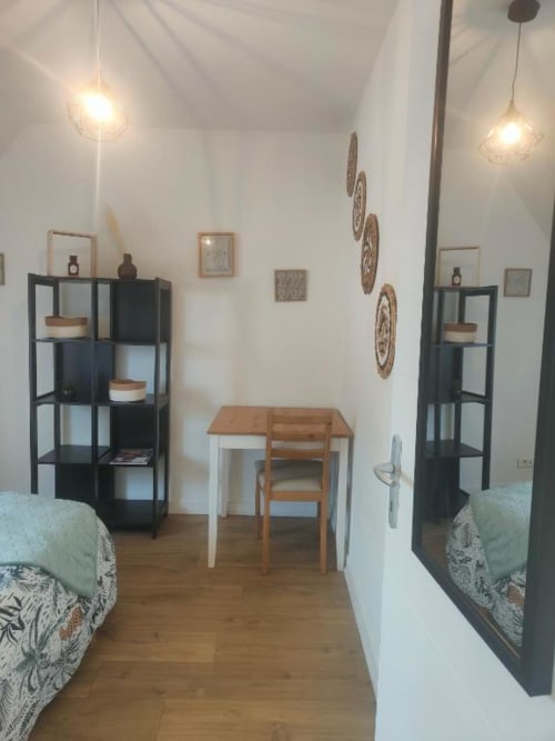 Studio lumineux à La Conciergerie de Nathalie à Dinan avec lits jumeaux, bureau, étagères noires et éclairage moderne