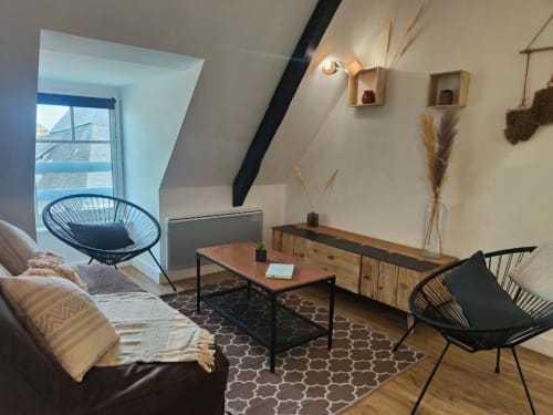 Élégant loft à La Conciergerie de Nathalie à Dinan avec mobilier en bois, aménagement moderne et vues sur toiture