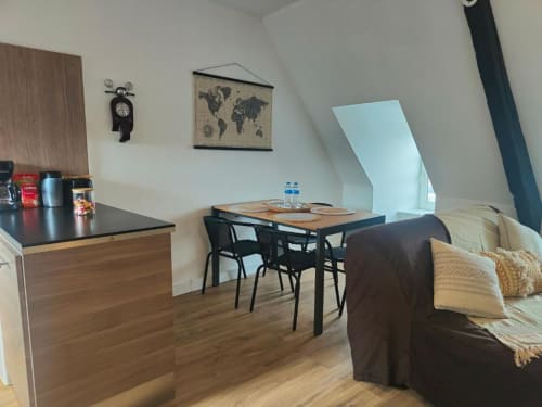 Appartement cosy à La Conciergerie de Nathalie à Dinan avec kitchenette, table à manger, canapé et chambre mansardée