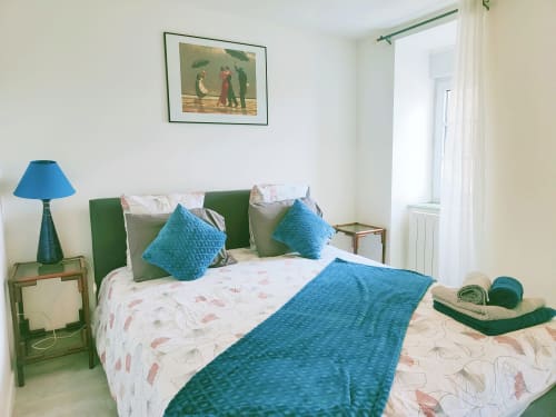 Chambre moderne à La Conciergerie de Nathalie à Dinan avec accents turquoise, tête de lit verte et literie florale