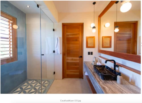 Baño moderno en villa Kaab Kaan House, Tulum con ducha tipo walk-in, lavamanos de mármol, iluminación colgante y detalles de madera