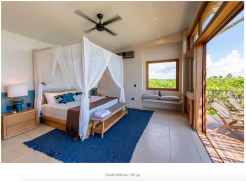 Lujosa habitación principal en villa Kaab Kaan, Tulum con cama con dosel, vista al mar, ventilador de techo y acceso a terraza