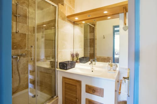 Une salle de bain avec douche à l'italienne et grand miroir au Mas des Olivades, une villa à Pernes-les-Fontaines, en Provence, France.
