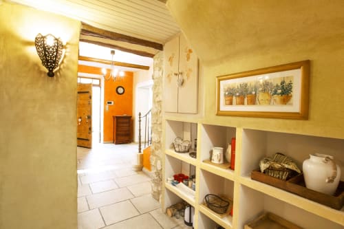 Un couloir avec étagères encastrées menant à une entrée lumineuse au Mas des Olivades, une villa à Pernes-les-Fontaines, en Provence, France.