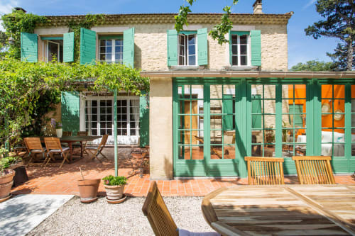 Une charmante villa en pierre avec des volets verts et un coin repas extérieur au Mas des Olivades, à Pernes-les-Fontaines, en Provence, France.