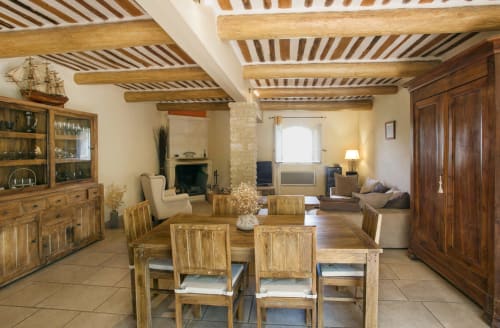 Salle à manger et salon rustiques avec meubles en bois et poutres apparentes au Mas des Olivades, une villa à Pernes-les-Fontaines, en Provence, France.