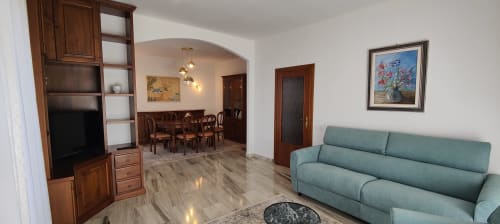 Spacious apartment living area with green sofa, wooden furniture, dining room, TV, and lake view at Villa Italia