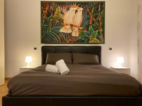 Camera da letto moderna all'Apartment GioviGemini di Treviso con letto nero, opere d'arte con uccelli tropicali e lampade comodino
