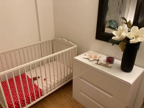 Moderna cameretta all'Apartment GioviGemini di Treviso con culla bianca, biancheria rossa, cassettone bianco, fiori e decorazioni