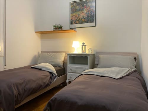 Accogliente camera doppia nell'Apartment GioviGemini di Treviso con biancheria scura, mensola in legno e lampada