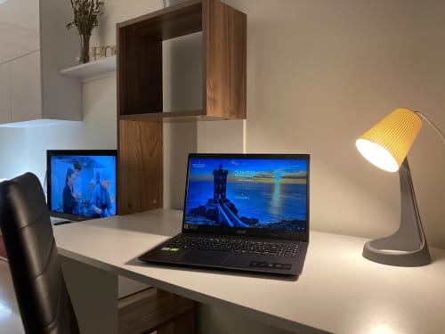 Moderno spazio di lavoro in appartamento a Treviso con laptop, doppio monitor e lampada da scrivania presso GioviGemini Apartment