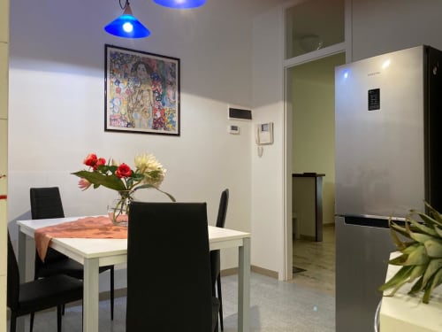 Elegante zona pranzo dell'Apartment GioviGemini a Treviso: tavolo bianco, sedie nere, fiori freschi e acciaio inox