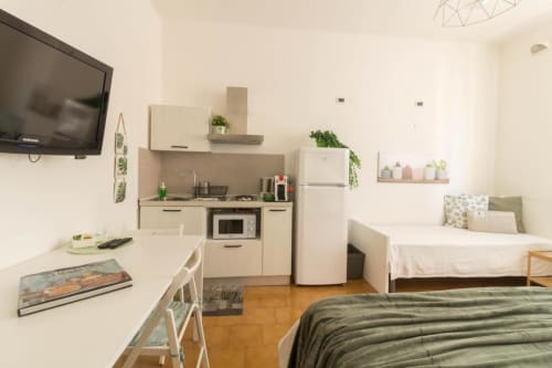 Monolocale a Ferrara con cucina, letto e zona living. Arredi moderni, mobili bianchi, pavimenti in legno.