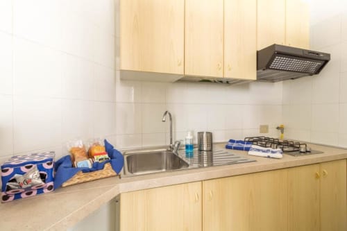 Cucina in legno chiaro con lavello, piano cottura e spazi di stoccaggio presso Appartamenti Ferrara a Ferrara