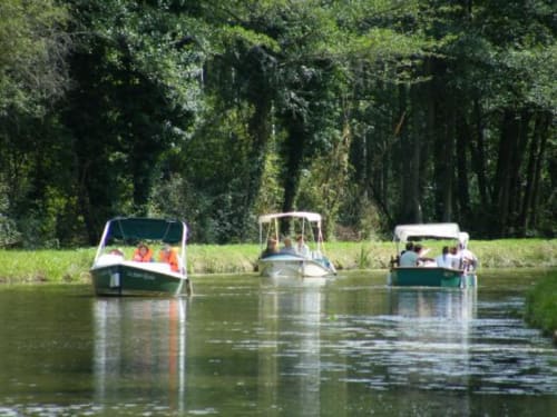 Trois bateaux amarrés sur la rivière calme près des berges boisées du Gîte du Miroir à Domérat, France