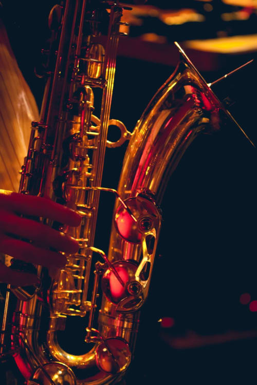 Golden saxophones illuminated in warm red and yellow lighting against dark background