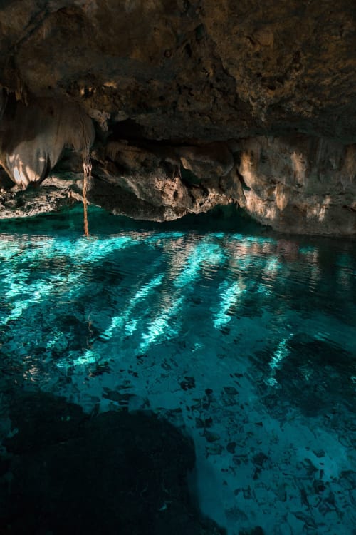 Underground cenote with turquoise waters and limestone cave formations in Tulum, Mexico