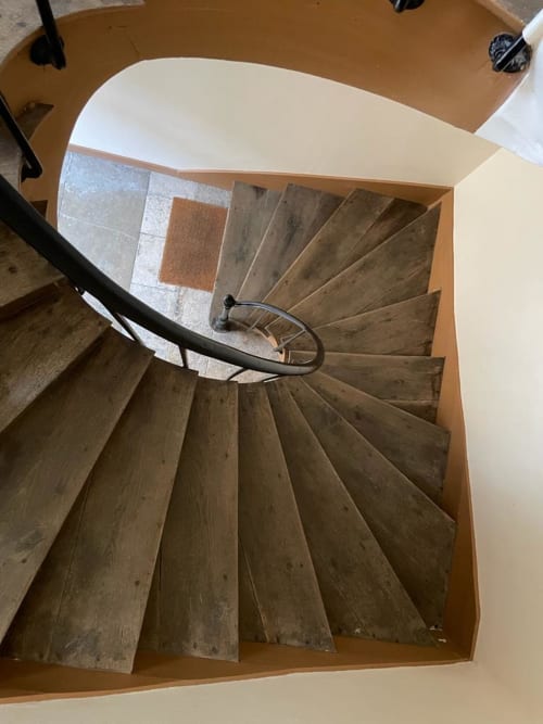 Escalier en spirale aux marches bois et rampe métallique à Chablis Appart, Chambre Blanchot, avec échantillons de revêtement sur le palier