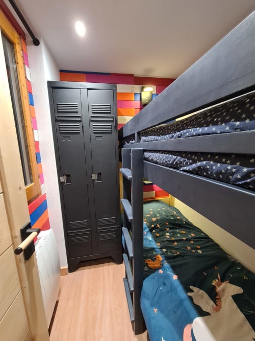 Chambre d'enfants colorée avec lits superposés noirs, parure étoilée et casiers à CMD Méribel Le Pralin