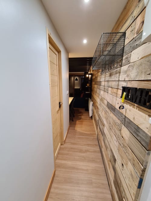 Couloir étroit avec rangements muraux en bois rustique à l'appartement CMD Méribel Le Pralin, murs blancs, porte en bois, ambiance chaleureuse