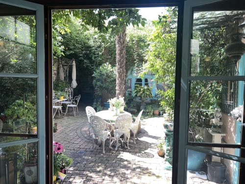 Terrasse de jardin luxuriant à Maison 1850 Paris avec cour lierre, mobilier bistro blanc et arbre mature