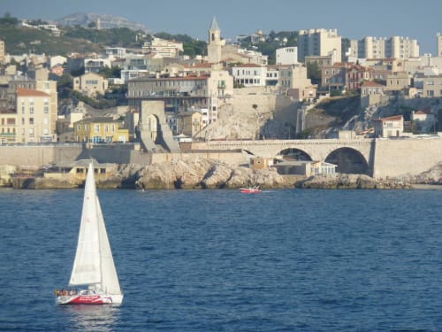 Voilier sur les eaux méditerranéennes avec le port historique de Marseille et ses bâtiments colorés à La Luna