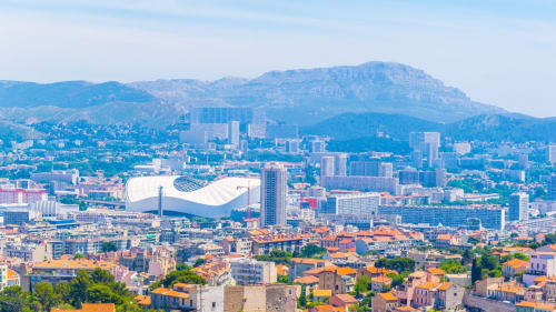 Vue panoramique de Marseille avec stade moderne et montagnes, destination La Luna BnB