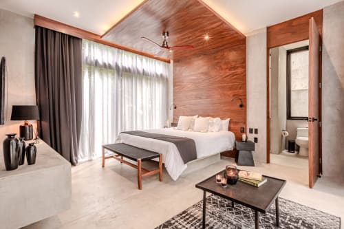 Dormitorio moderno en villa Karmond House en Tulum con paredes de madera, ropa de cama blanca, vistas al jardín y baño ensuite