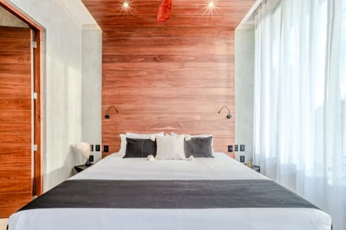 Moderno dormitorio en villa Karmond House, Tulum, con pared de madera, ropa de cama blanca y vistas al jardín a través de cortinas translúcidas