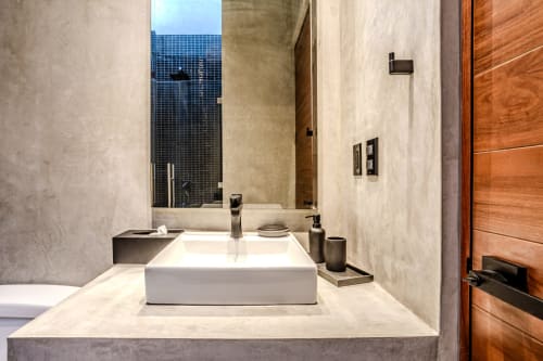 Baño moderno con lavamano blanco tipo recipiente y accesorios negros en la villa Karmond House, Tulum