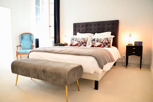 Chambre luxueuse au Pavillon Des Millesimes à Lussac avec tête de lit capitonnée, banc rayé, fauteuil bleu et design moderne