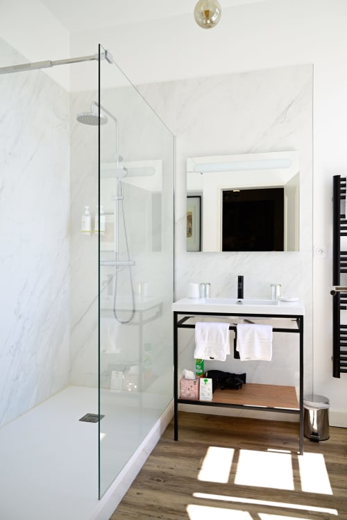 Modern bathroom at Pavillon Des Millesimes Lussac with marble shower, black vanity, and wooden flooring
