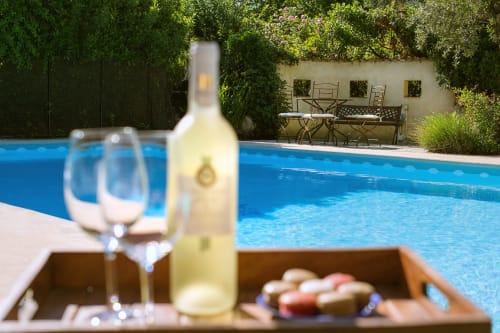 Une bouteille de vin, deux verres et des macarons sur un plateau près de la piscine au Mas des Olivades, une villa à Pernes-les-Fontaines, en Provence, France.