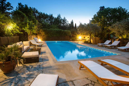 espace piscine lumière du soir avec des chaises longues et de la verdure au Mas des Olivades, une villa à Pernes-les-Fontaines, en Provence, France.