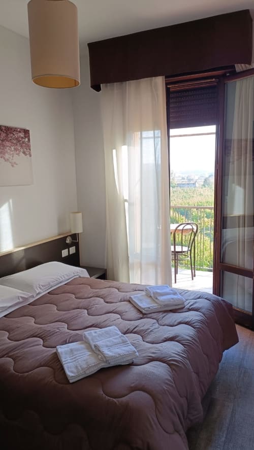 Camera Hotel Eden a Vignola con balcone, biancheria trapuntata e luce naturale dalle porte-finestre della terrazza