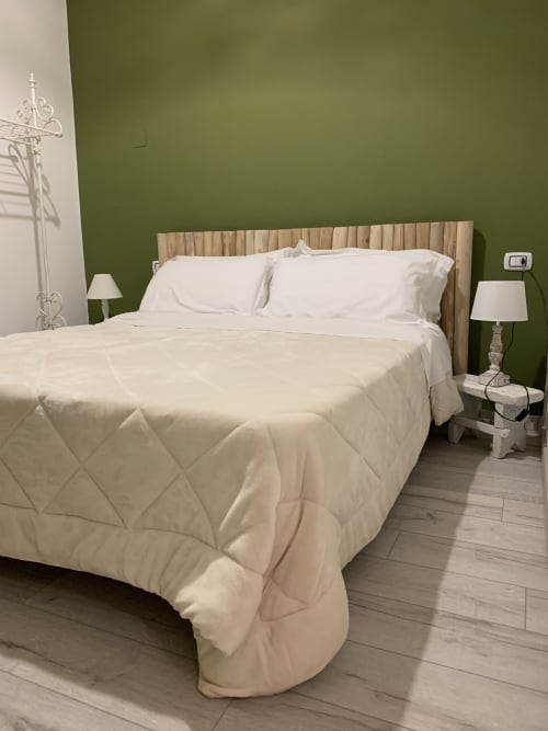 Spaziosa camera doppia presso Agriturismo Il Pomo d'oro con biancheria bianca, testata in legno, pareti verdi e comodino con lampada
