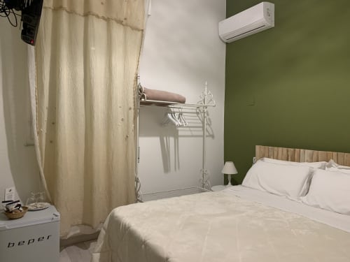 Camera matrimoniale moderna presso Agriturismo Il Pomo d'oro ad Assemini con parete accent verde, biancheria bianca, aria condizionata