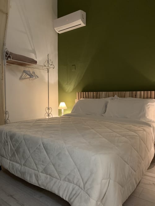 Camera moderna presso Agriturismo Il Pomo d'oro con letto bianco, parete verde, aria condizionata e attaccapanni