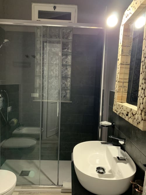 Bagno moderno all'Agriturismo Il Pomo d'oro con box doccia in vetro, lavabo bianco e specchio riscaldato ad Assemini