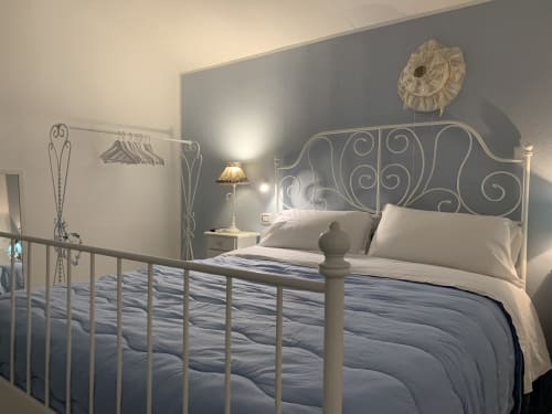 Camera Celeste presso Agriturismo Il Pomo d'oro ad Assemini con letto in ferro battuto ornamentale, biancheria bianca e vista sul giardino
