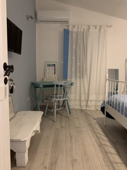 Stanza affascinante presso Agriturismo Il Pomo d'oro ad Assemini con tavolo da pranzo, letto in metallo bianco e vista sul giardino