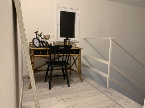 Spazioso home office con scrivania in legno, sedia nera, TV a parete, decorazione bicicletta e moderne ringhiere bianche
