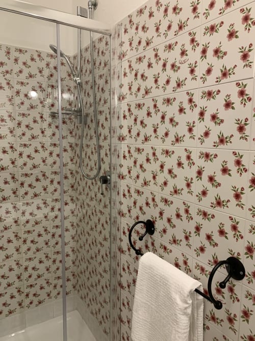 Moderna cabina doccia con piastrelle a motivo floreale presso l'Agriturismo Il Pomo d'oro ad Assemini, con portasciugamani bianco e