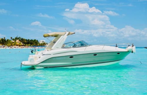 Lujoso yate blanco y verde anclado en aguas turquesas del Caribe, cerca del resort de playa Tulum